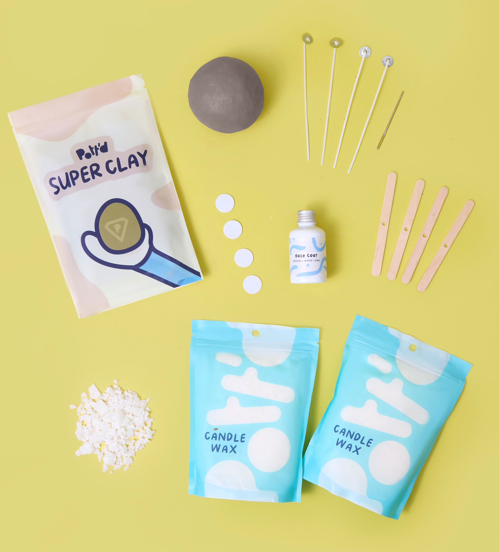 Crafting kit with beige clay, candle wax, sticks, and a base coat on a vibrant yellow backdrop for DIY projects.