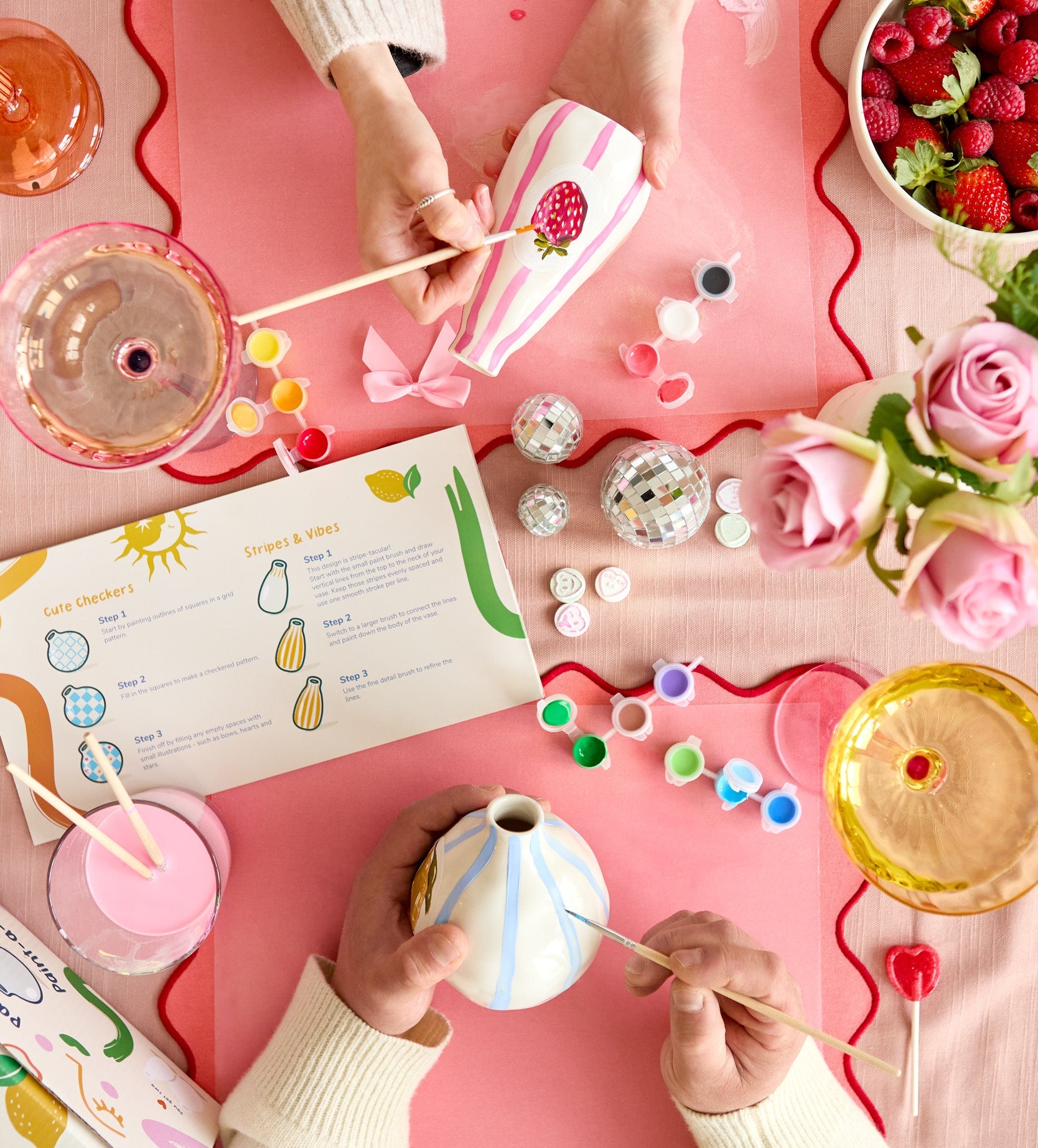 Four paint markers in transparent barrels on a white surface, each creating a unique wavy line pattern.