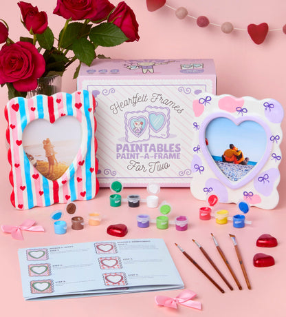 Heart-shaped paintable picture frames set with brushes, colorful paints, instructions, and pink-themed packaging.