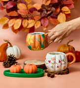 Colorful Halloween teapots on a peach background, featuring a smiling pumpkin and witch-themed designs.