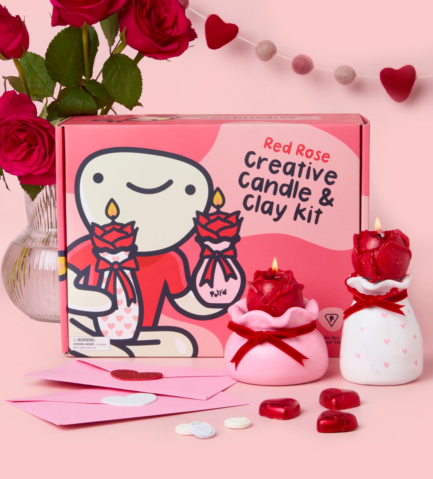 Red Rose Creative Candle and Clay Kit being held by hands over a pink table with roses and heart decorations.