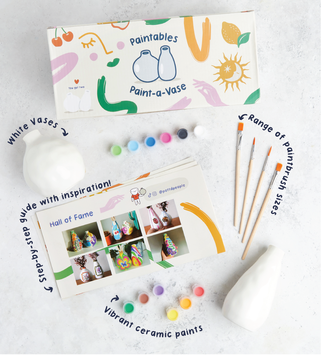 Heart-shaped DIY mug painting kit with colorful paints, brushes, and a pink and white "I love you" design on a white background.