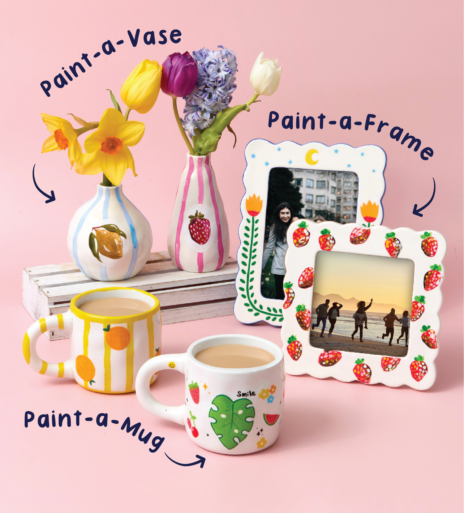 Stack of hand-painted ceramic mugs with playful designs including rainbow, cherries, and planets on a kitchen counter.