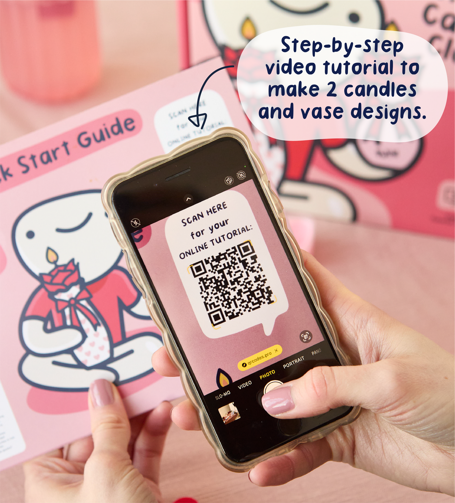 Hand holding pink air dry clay figure with red velvet bow, surrounded by crafting tools on a pink table.