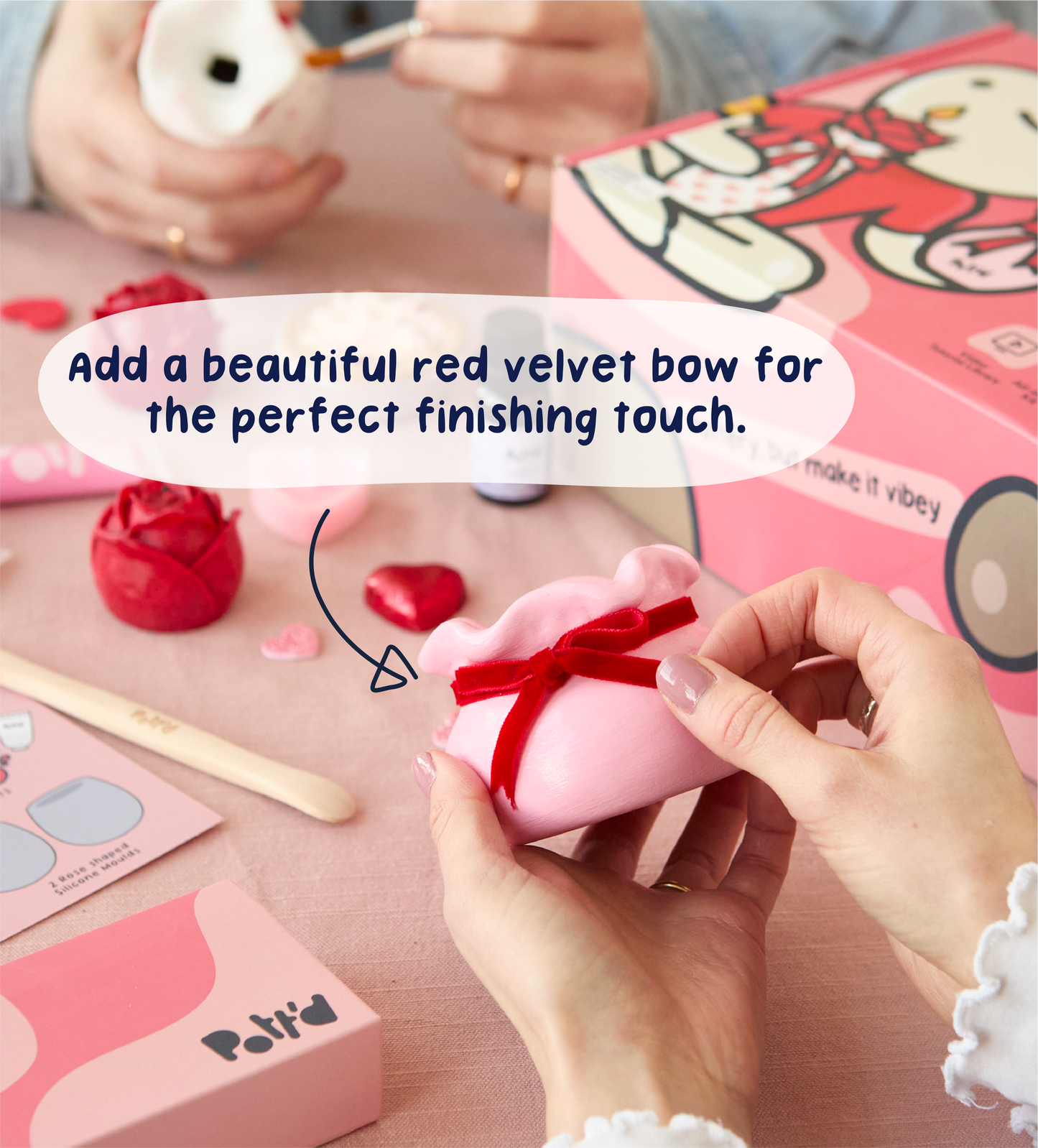 Hands holding phone scanning QR code on pink tutorial guide for making candles and vase designs.