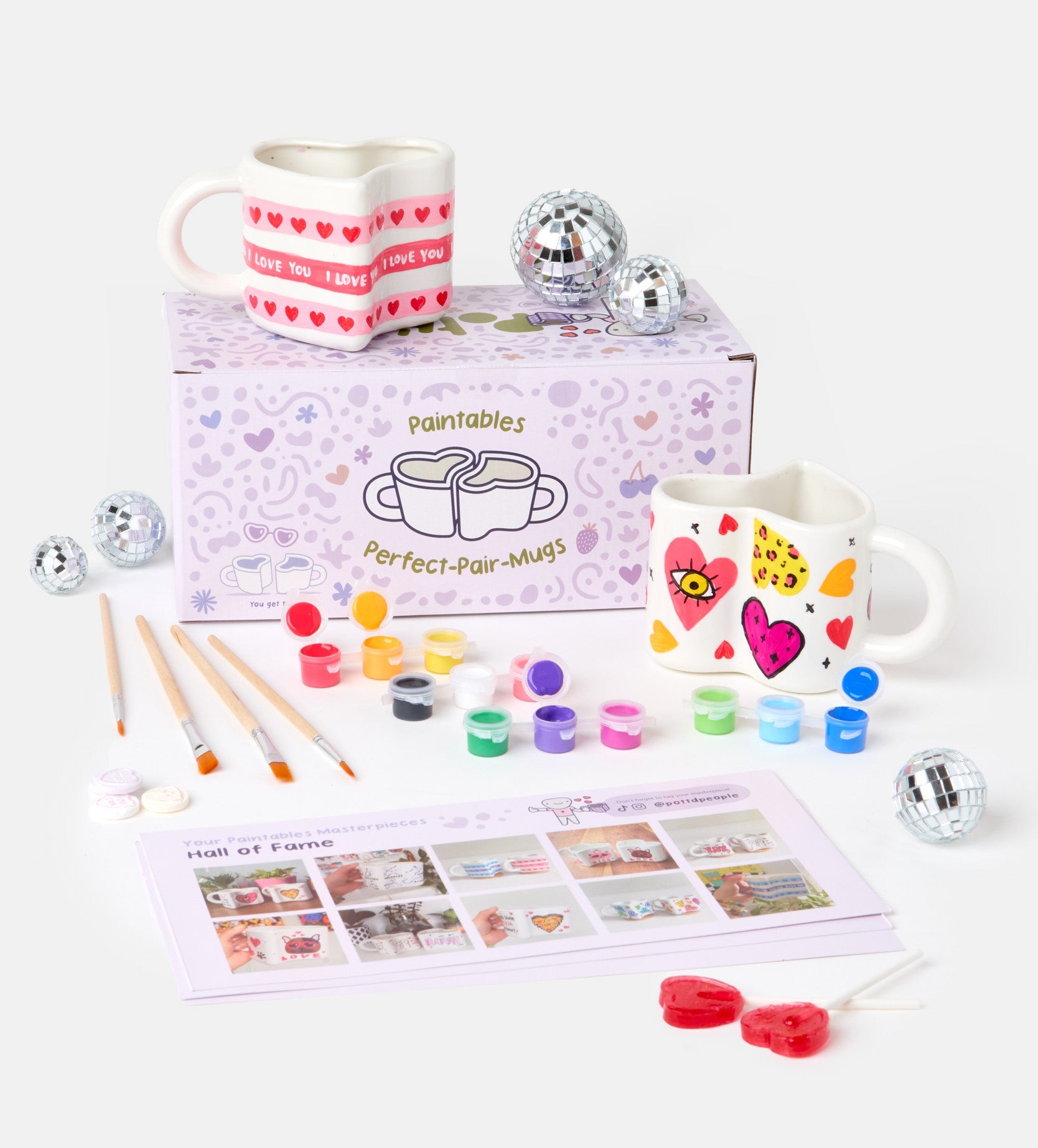 Pottery kit with instruction guides, sculpting tools, paints, gloss varnish, and clay bags on a light textured surface.
