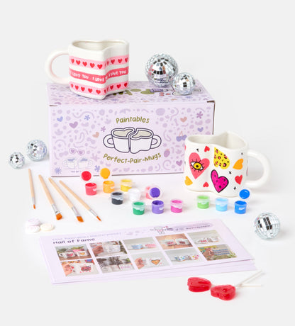 Pottery kit with instruction guides, sculpting tools, paints, gloss varnish, and clay bags on a light textured surface.