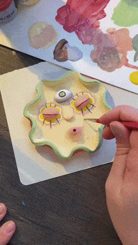 GIF of someone adding final touches to a face incense burner and then lighting incense 